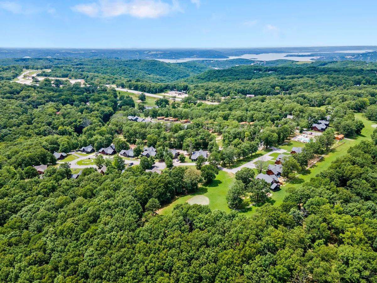 An expansive scenic overview of the resort community set against stretches of greenery and a distant water body. The image evokes a sense of privacy and connection with nature, showing the broader landscape couples can explore, including hiking trails and scenic lookouts.