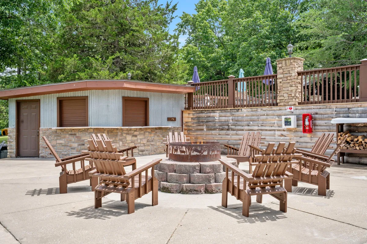 A cozy fire pit with Adirondack chairs encircled by trees, offering a warm and private spot to unwind outdoors. The inviting setup suggests an intimate evening setting, perfect for couples to relax, share stories, or enjoy stargazing together.