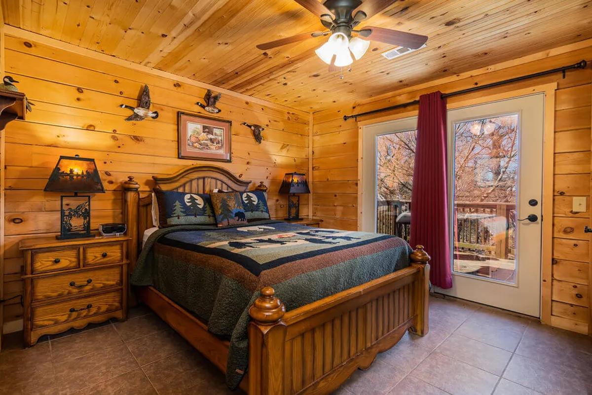 A rustic bedroom with a wooden bed, decorative pillows, nature-themed lamps, and a window with curtains that lets in soft daylight. The décor combines comfort with a touch of nature, perfect for unwinding after a busy day.